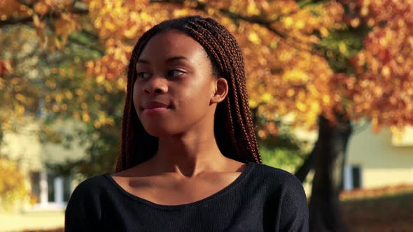 Young Beautiful Black Woman Smiles To Camera in the Park in Autumn Day