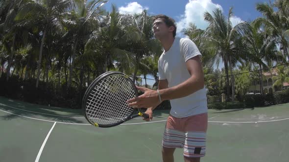 A young man playing tennis with his girlfriend.