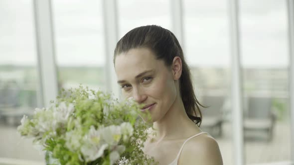 Young woman smelling bouquet of fresh flowers