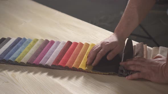 Samples of Colored Fabric for Making Furniture in the Hands of a Bearded Man in an Authentic