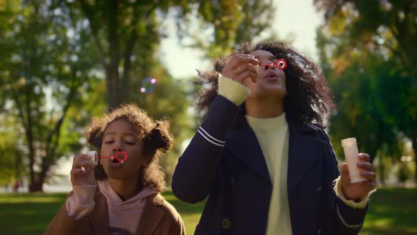 Parent Kid Blowing Soap Colorful Bubbles in Green Sunny Park Together Portrait