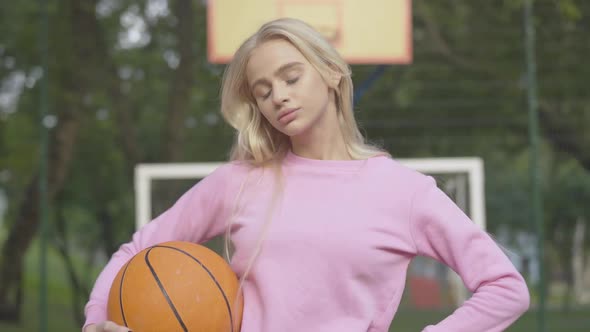 Camera Approaches To Confident Young Sportswoman Posing with Basketball Ball on Outdoor Court