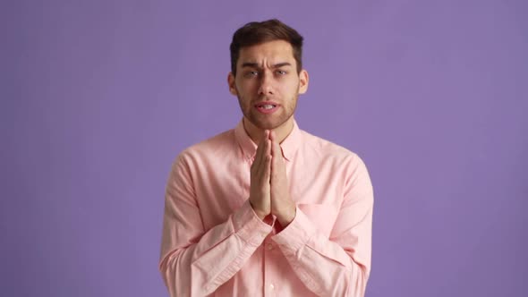 Studio Portrait of Excited Young Man Holding Hands Folded in Prayer Beg About Something Make Wish