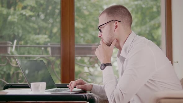 Businessman Working on a Computer Outside the Office in a Cafe