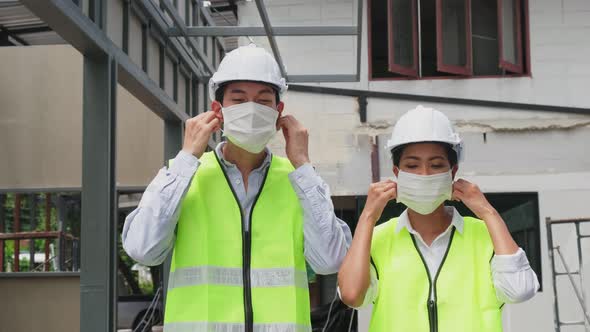 Asian workers people removes protective face mask onsite of architecture due to COVID 19 pandemic.