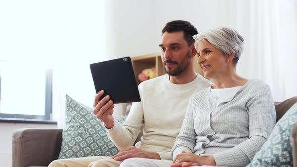 Old Mother and Adult Son with Tablet Pc at Home