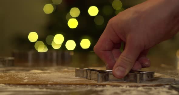 Male hand cutting the flattened gingerbread dough with dog shaped cutting form