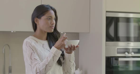 Woman eating breakfast in kitchen