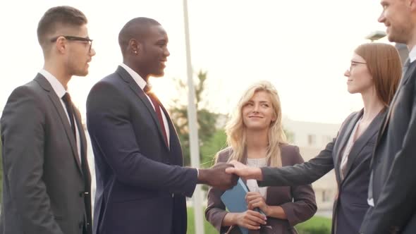 Businesspeople Shaking Hands and Smiling Outdoors