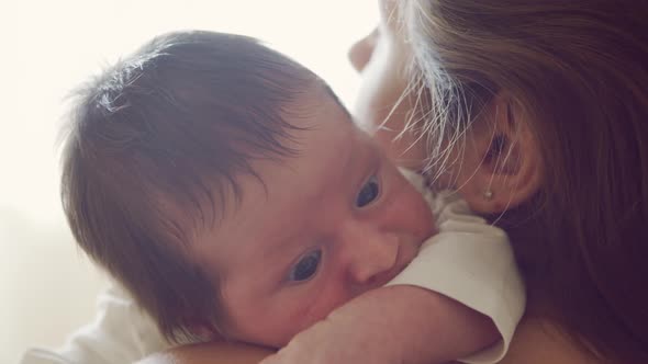 Newborn baby boy and his mother at home. Close-up portrait of the infant