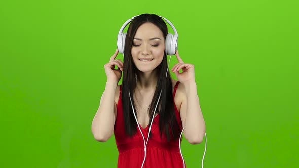 Girl Listens To Cheerful and Energetic Music Through Headphones, Green Screen, Slow Motion