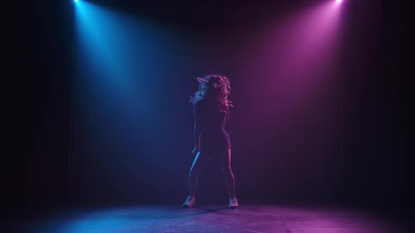 Slim Long Legged Young Female Dancer Practices Jazz Funky Movements in a Dark Studio. Silhouette of