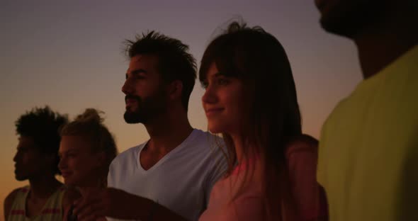 Young adult friends having fun on the beach at night with sparklers 4k