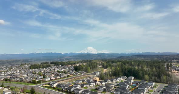 Aerial shot pulling away from Mount Rainier to reveal more and more houses.