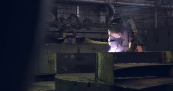 A Professional Worker in a Protective Mask Works with a Grinder in a Factory