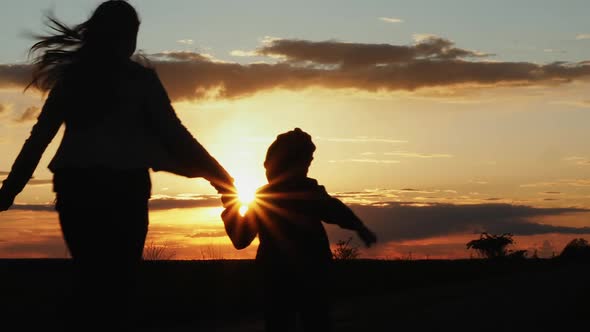 Silhouettes of Happy Family Runs at Sunset