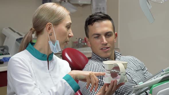 Handsome Man Showing Thumbs Up Sitting in Dental Chair, Talking To His Dentist 