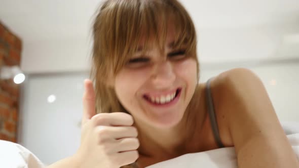 Thumbs Up by Woman Lying in Bed, Close Up of Face