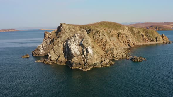 Island with High Vertical Rocks Among the Sea