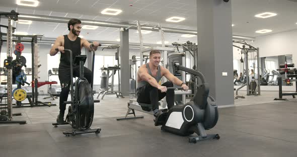 Two Athletic Men Perform Cardio Exercises at Gym