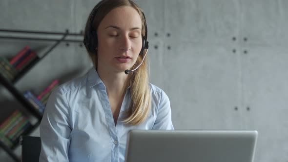 Businesswoman Sitting at Desk, Making a Call, Using Headset and Laptop