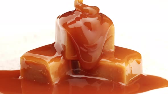 Melted caramel sauce flowing on caramel candies close up
