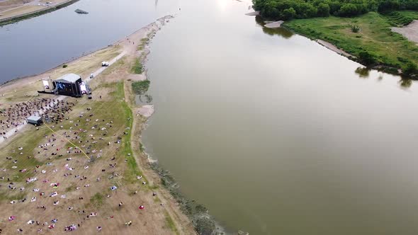 Crowd of people at music stage in Nemunas and Neris river conjunction, aerial fly over view