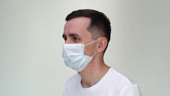 Smiling Young Happy Man Taking Off Medical Mask on White Isolated Background.