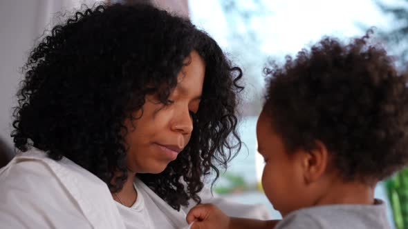 Closeup Portrait of Confident Young African American Mother Talking to Cute Little Son with Blurred