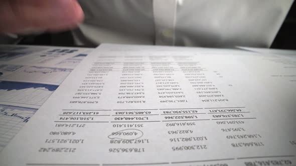 Accountant Analyzing Business Marketing Data on Paper Dashboard at Office Table