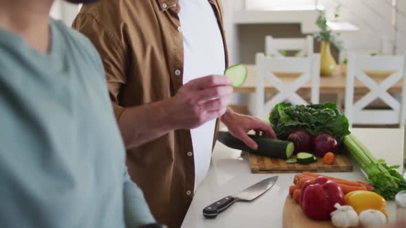 Multi ethnic gay male couple preparing food in kitchen