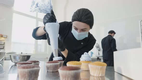 Confident Professional Confectioner Decorating Muffins with Blue Topping