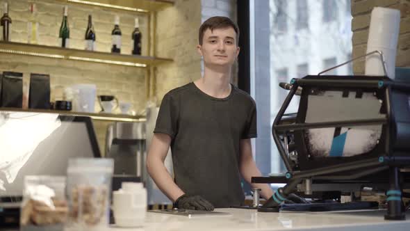Confident Young Caucasian Barista Posing at Coffee Machine in Cafe