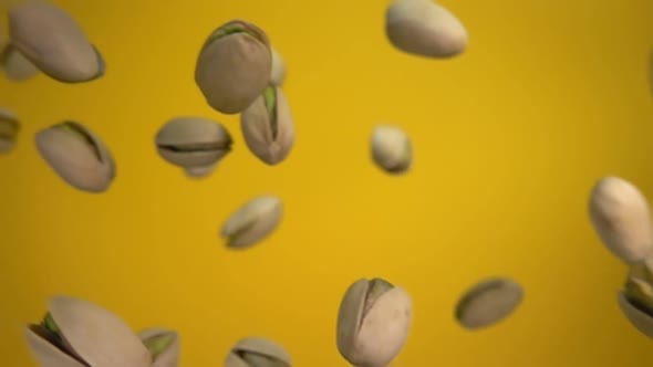 Closeup of Salted Pistachios Falling on a Yellow Background