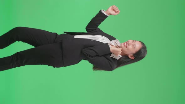 Side View Of A Smiling Asian Business Woman Dancing While Standing On Green Screen Background