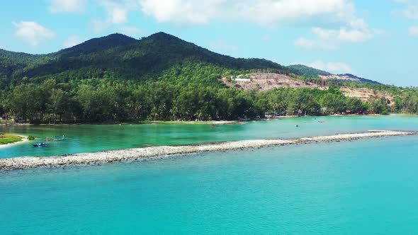 Unspoiled turquoise lagoon with a sandbank, sand beach and hilled jungle in the background. Thailand