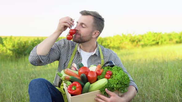 Happy Farmer Holding Basket with Fresh Harvested Vegetables and Smiling in Camera on Countryside