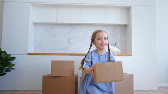 Little preschooler girl in blue dress takes brown cardboard package