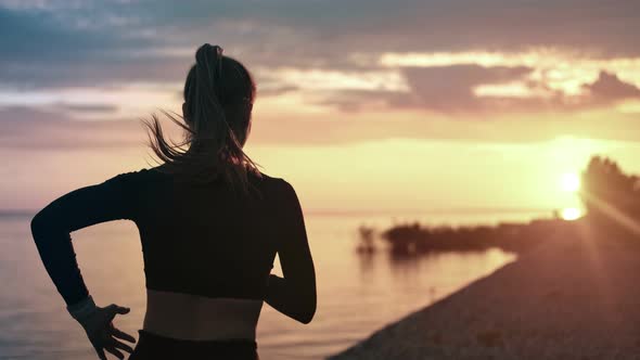 Back View Sportswoman Running at Seashore with Dramatic Sky and Sunshine