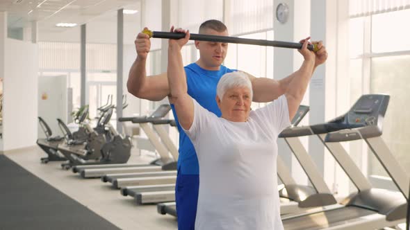 Elderly Woman Does a Stretching Exercise in the Gym