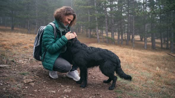 Young Woman Stroking Her Cute Black Dog While Walking Her in the Autumn Forest