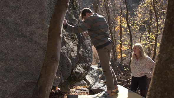 Man and woman as they prepare to climb boulder