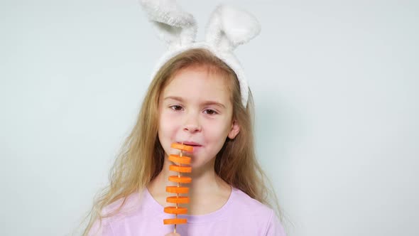 A Girl Wearing Bunny Ears Eats Carrot Slices