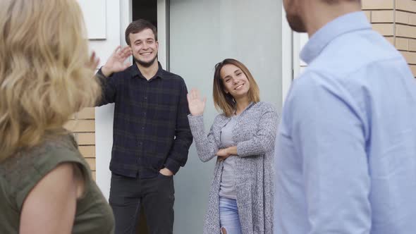 Married Couple Leaving Home of They Friends Waving Hands