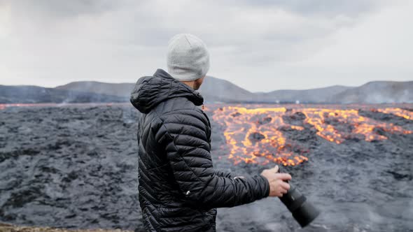 Photographer Looking Through Camera To Flowing Lava In Landscape