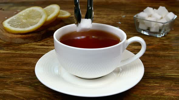 Bag of Tea Brewed in White Ceramic Mug Dipped in Boiled Hot Water and Two Pieces of Refined Sugar