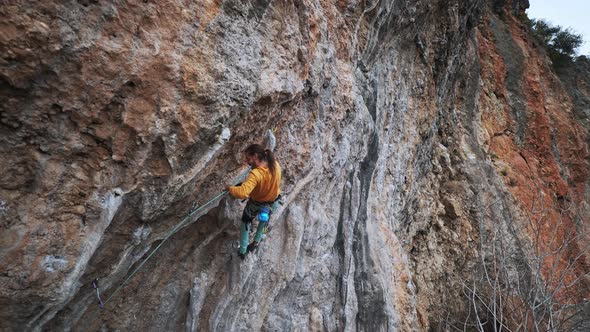 Slow Motion Male Rock Climber Hanging on Hand on Rocky Wall on Hard Challenge Route and Clipping