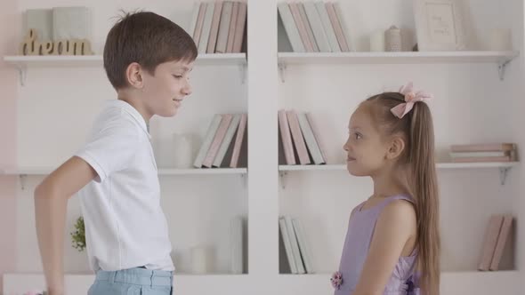 Caucasian Boy Giving Bouquet of Flowers To Shy Little Girl, Side View Portrait of Cute Gentleman