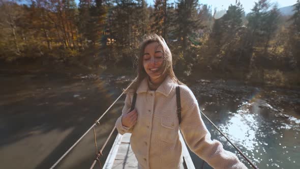 Slow Motion Portrait of Happy Beautiful Young Woman Tourist Standing on Wooden Suspension Bridge