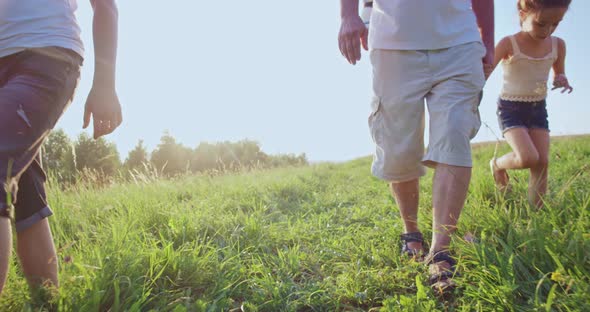 Father with Five Kids Walking Down Green Hillside in Summer